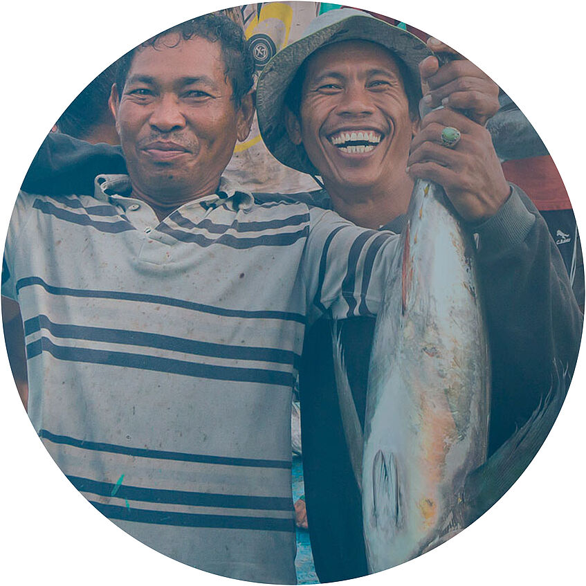 Fishermen from Indonesia grinning in camera while presenting their fish prey