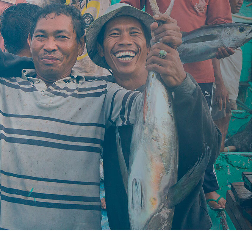Fishermen from Indonisia grinning in camera while presenting their fish prey</p>
<p>